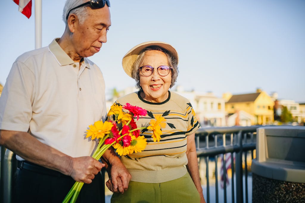 Happy elderly couple holding flowers outdoors, enjoying togetherness and love.